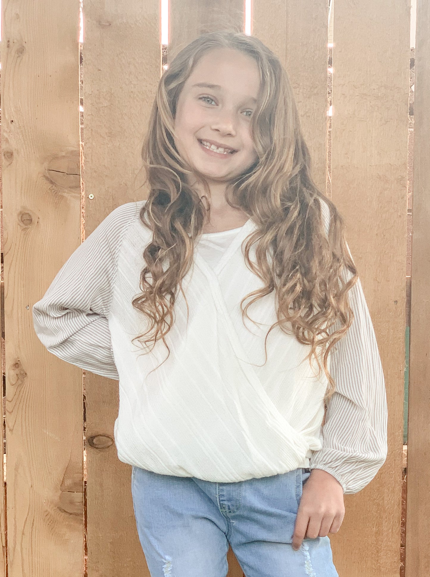 Little girl in our cream, ribbed balloon sleeve top.